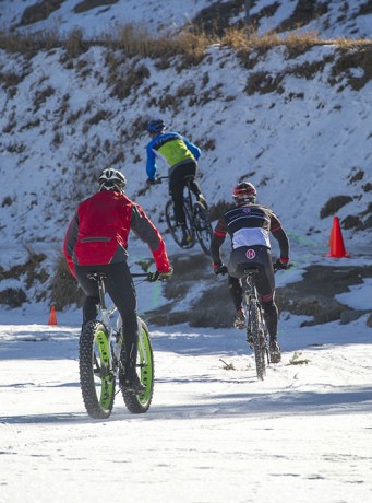 Mountain bike racers make the transition from the lake to icy and snow-packed hillsides.